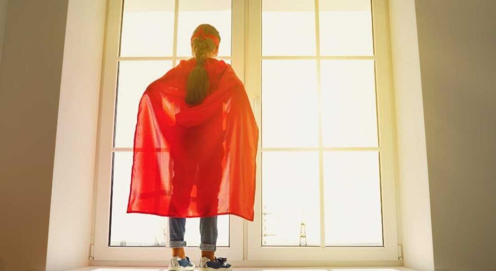 girl in superhero costume looking out window