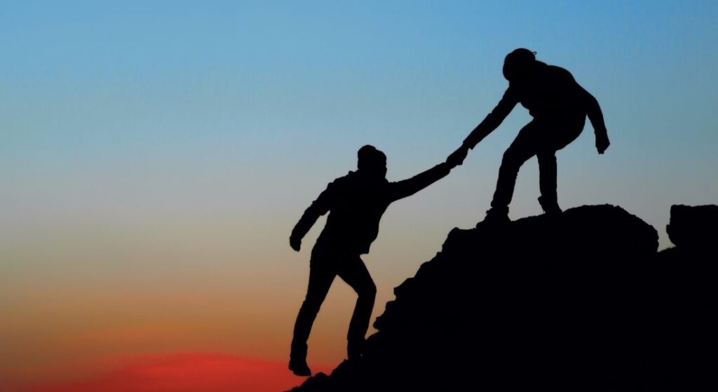 friends helping each other climb rocks