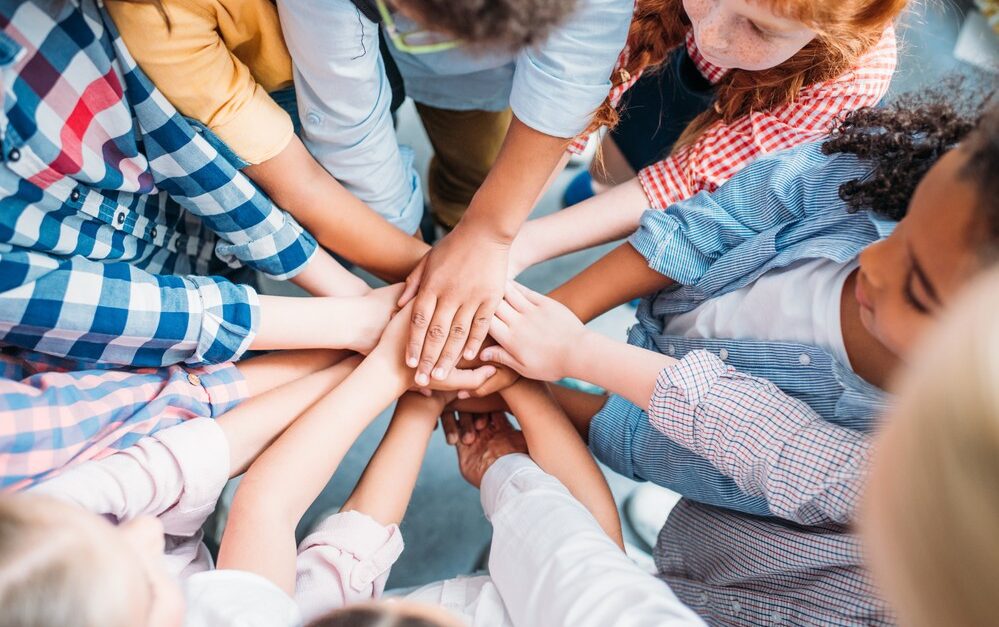 several kids with hands in circle from birds eye view