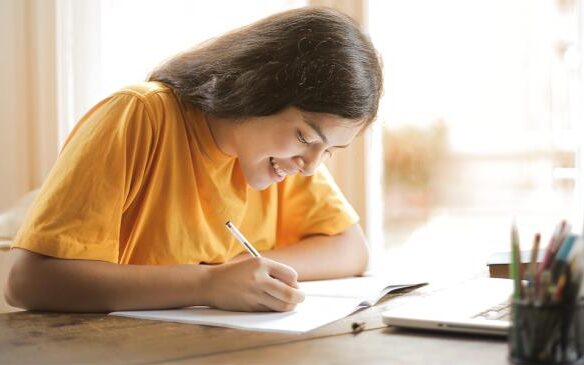 kid in yellow shirt writing in notebook