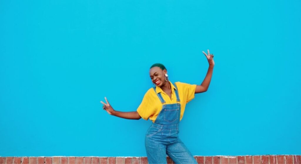 woman peace sign in front of blue wall