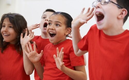 four kids in red t-shirts playing theatre game