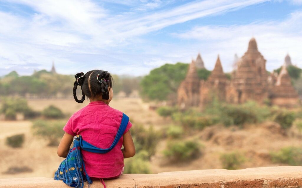 young girl sitting on stone wall overlooking landscape