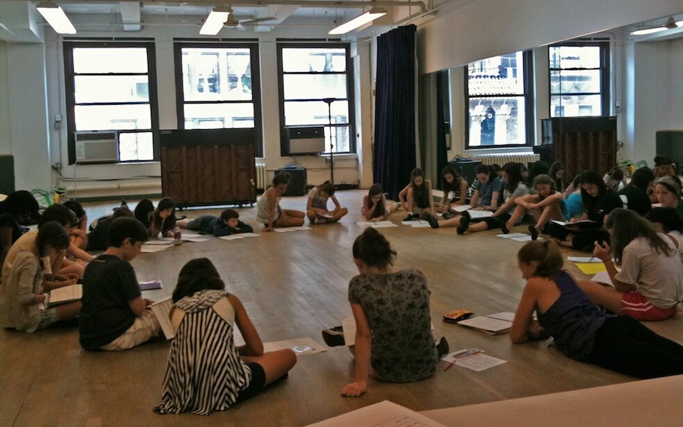 kids in studio sitting in circle with scripts