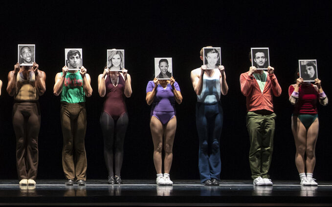 a chorus line cast holding headshots up in front of their faces