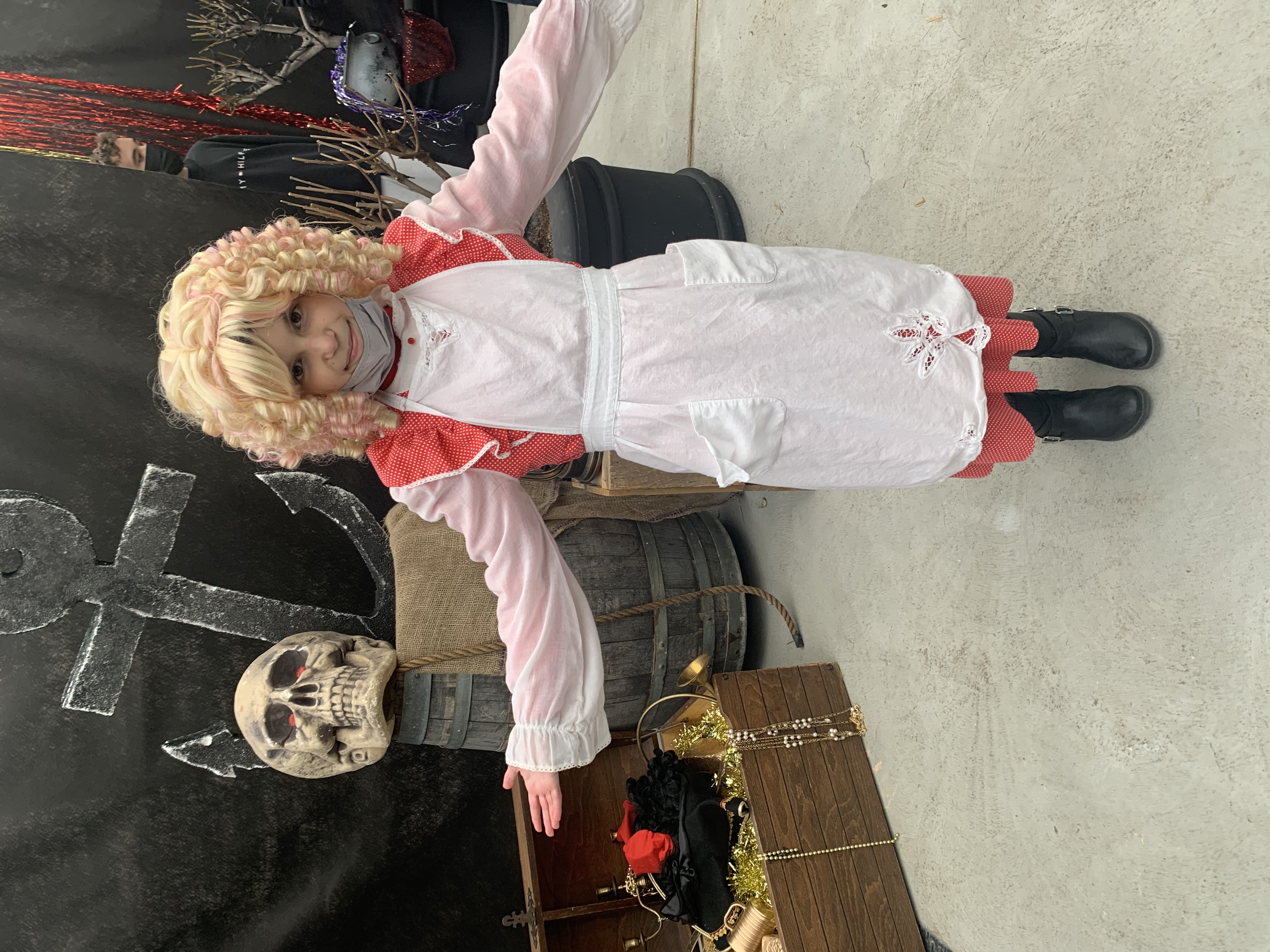 charlotte in costume blond wig with props behind her skull anchor treasure chest